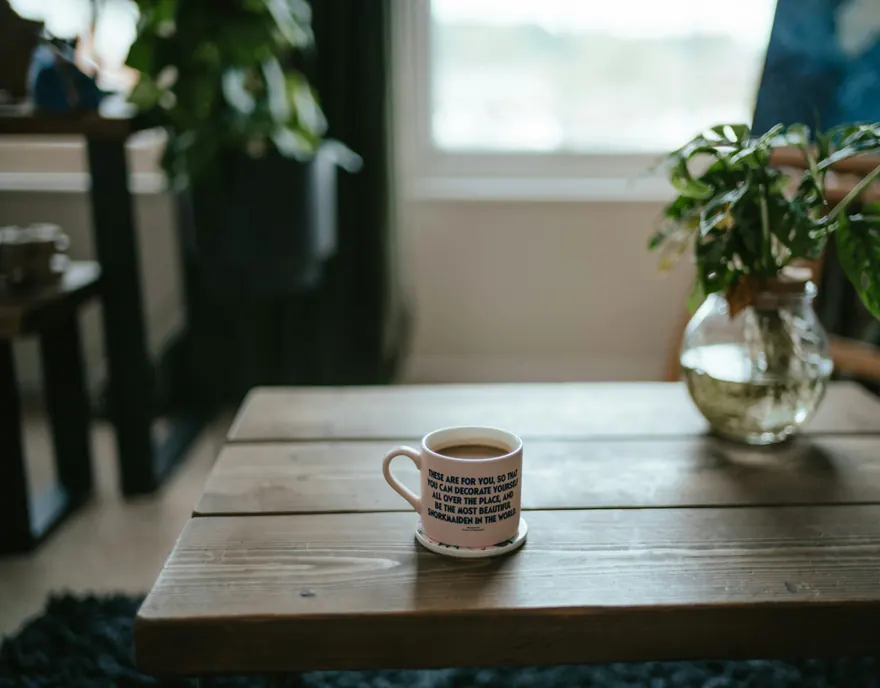 A mug on a wooden table by a window