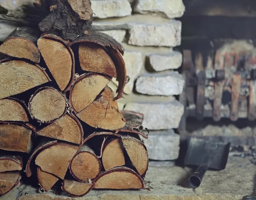 Split firewood stacked against a stone wall